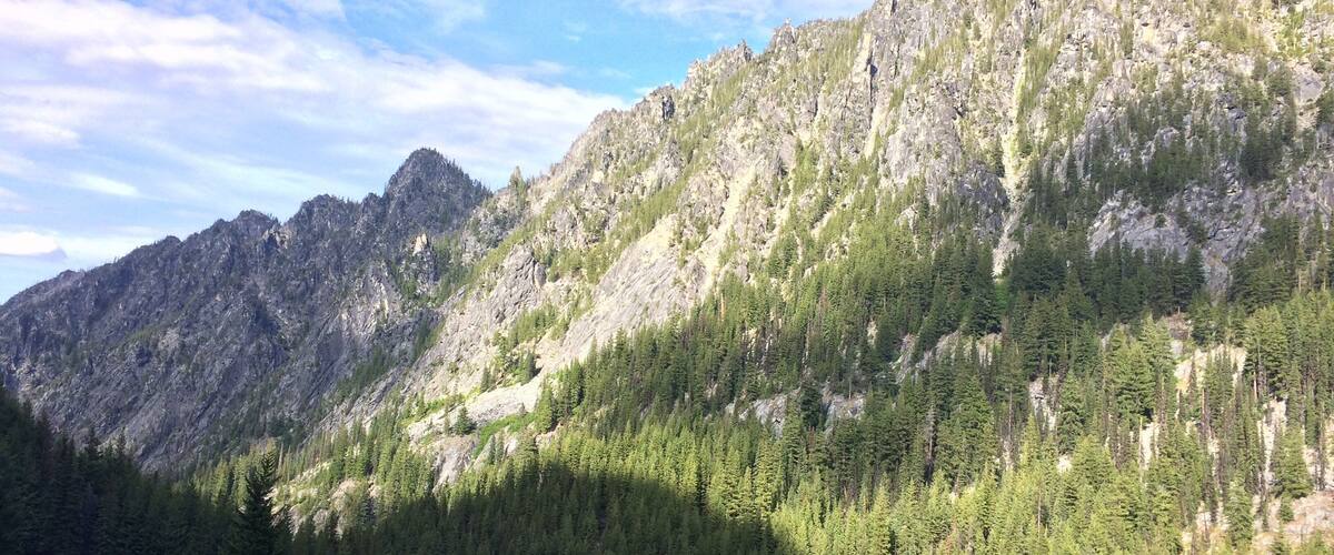 A mountainous landscape with dense forests and rocky cliffs.