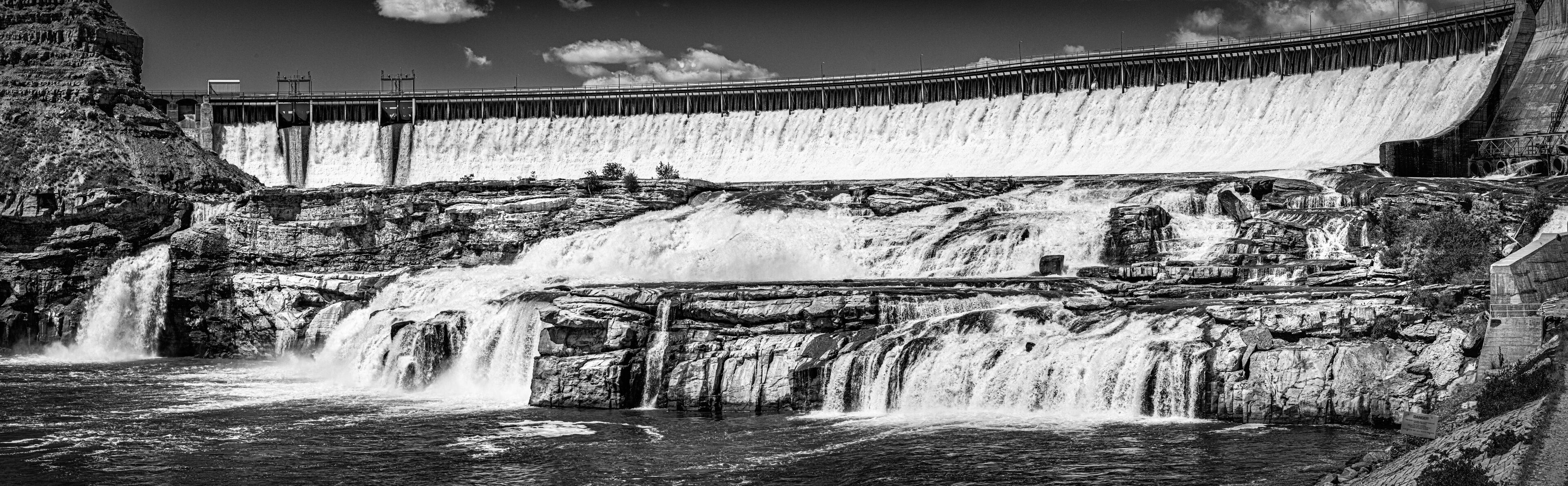 A large dam with multiple spillways releasing water into a river.