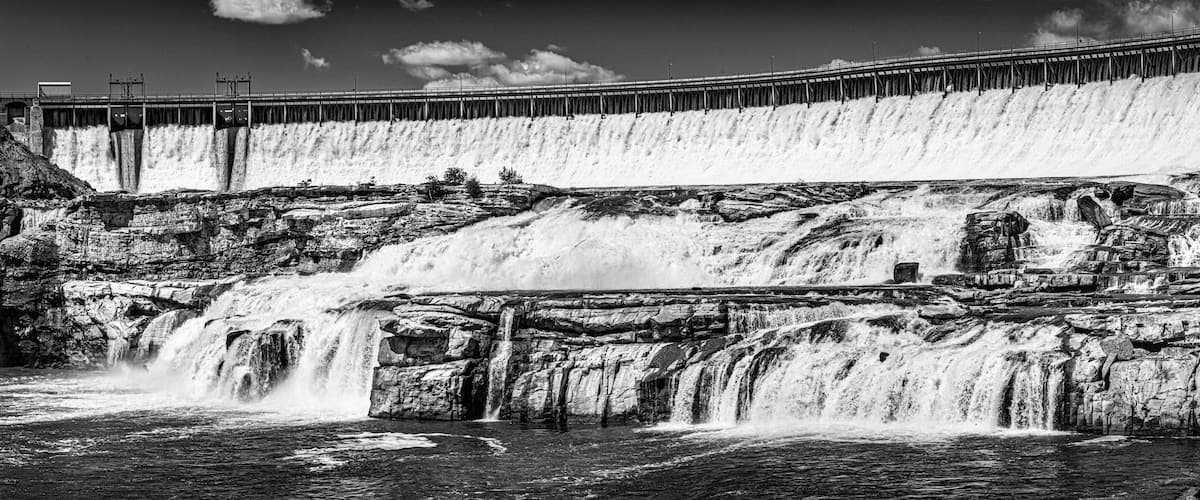 A large dam with multiple spillways releasing water into a river.