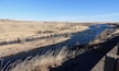 A river winding through a dry, hilly landscape with sparse vegetation and a clear sky.