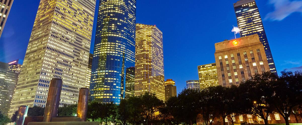 A cityscape with tall skyscrapers and a park area.