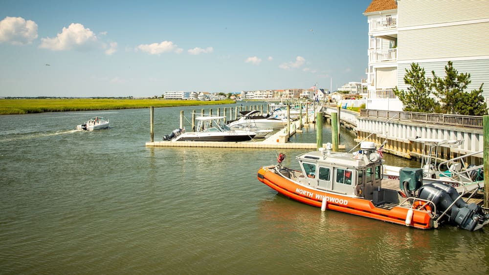 A marina with boats docked, a bridge, and a white building with a balcony.