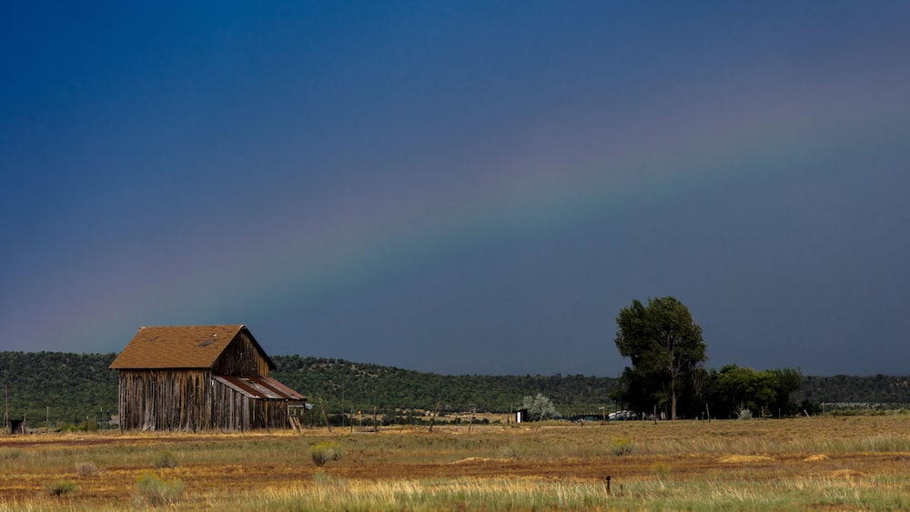 Dramatic view of rainbow over a western barn near Norwood Colorado in the LaSalle Mountains