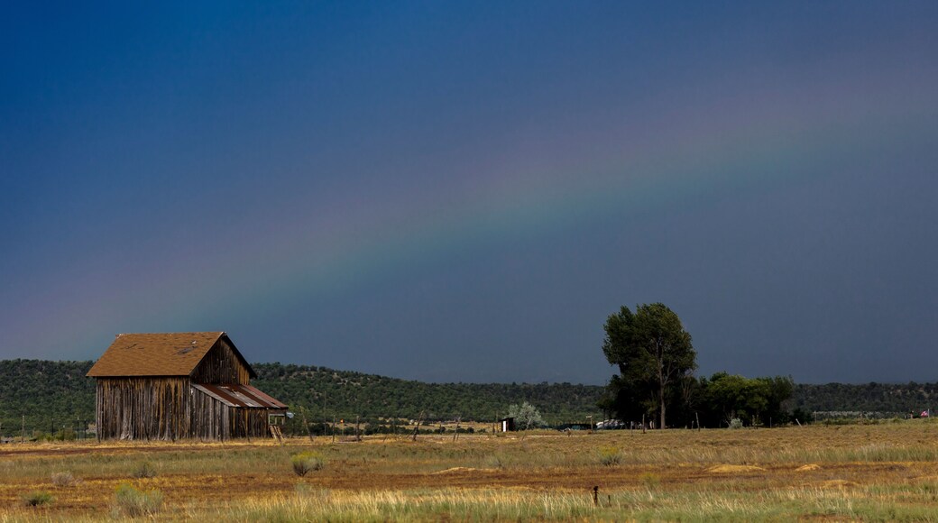 Dramatic view of rainbow over a western barn near Norwood Colorado in the LaSalle Mountains