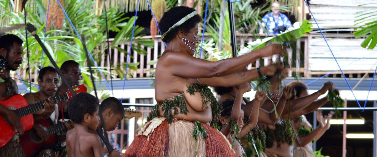 A traditional dance performance with participants wearing grass skirts and feathered headdresses.