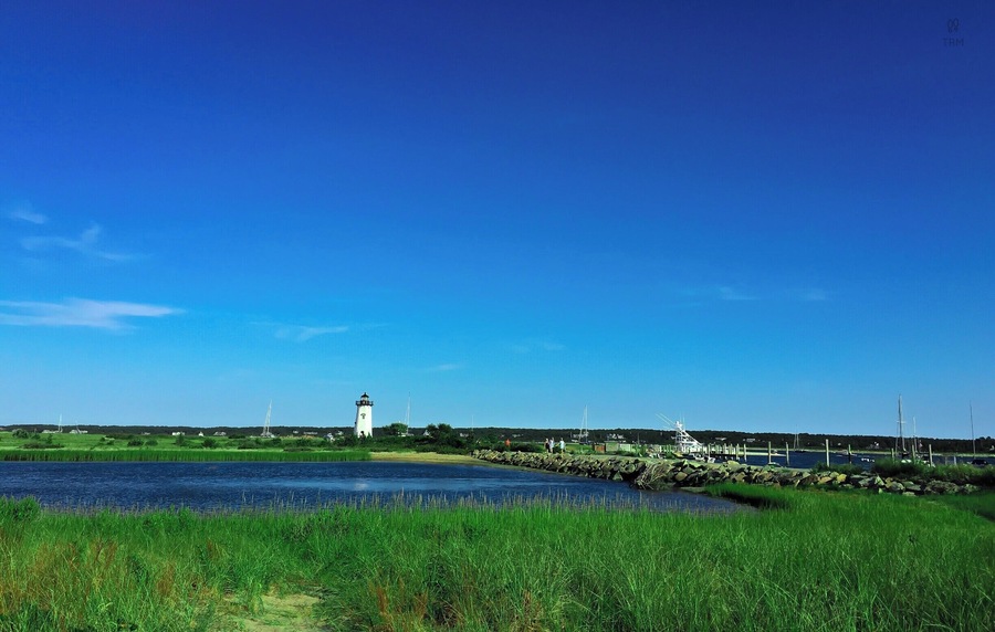 Sandy beaches, farmlands, fishing docks, harbor towns and tall lighthouses, Its Martha's Vineyard! It is around an hour of boat ride from Cape Cod to the Oak Bluffs. MV accessible only by boat or air. 
This picture was of course taken in summer :) Bright sunny day with blue sky and lush green. In the background is the famous east chop lighthouse. The best of my memories of MV are from East Chop.   We rented a bright Red scooter near the Oak Bluffs harbor after getting off from ferry, kicked off our slippers, rode to the sunset ;) I meant we drove to East Chop:)
Must Do : Get that pretty but awfully slow red scooter, drive to the light house, live the dream :)