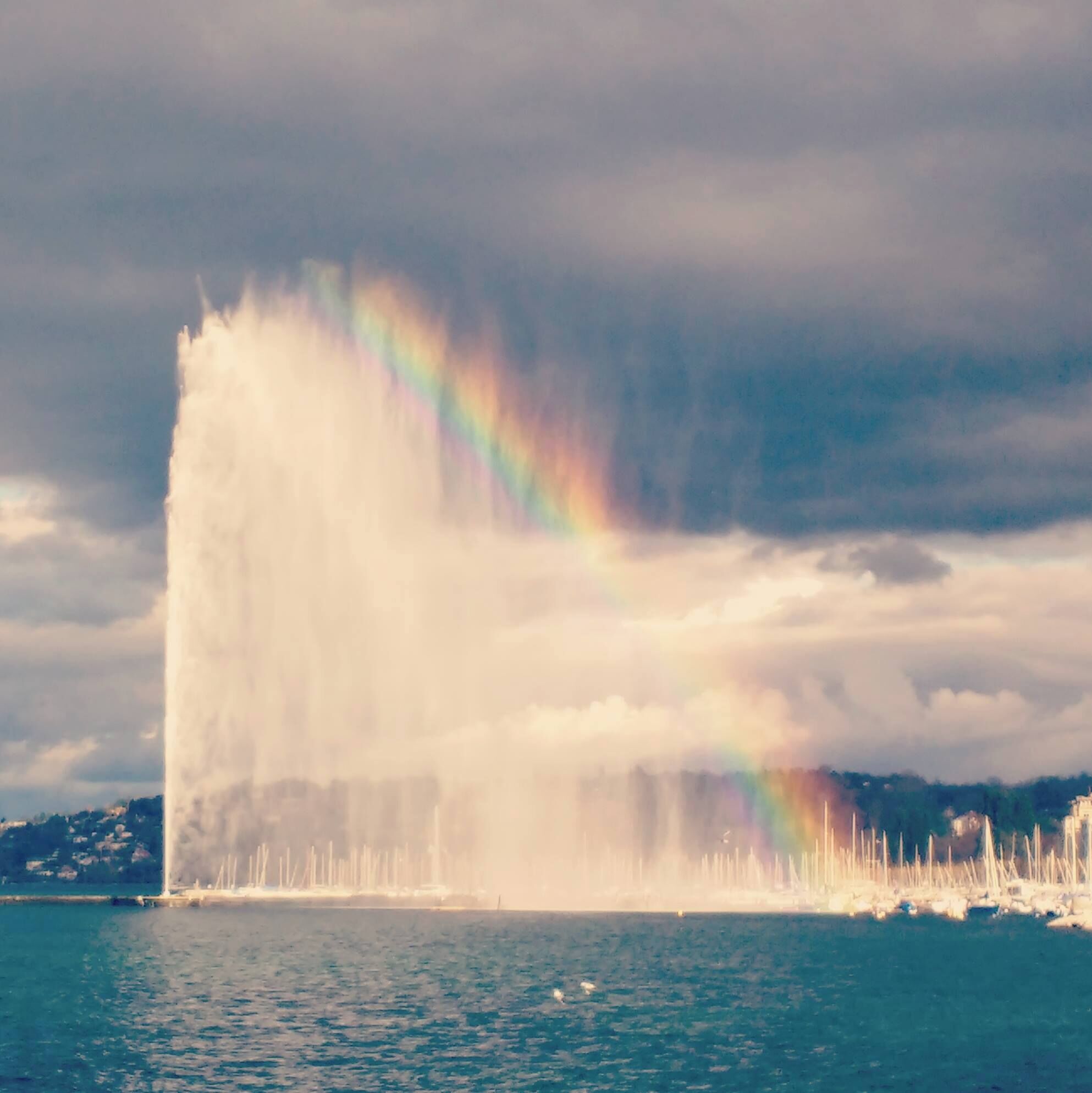 Une fontaine avec un arc-en-ciel en arrière-plan.