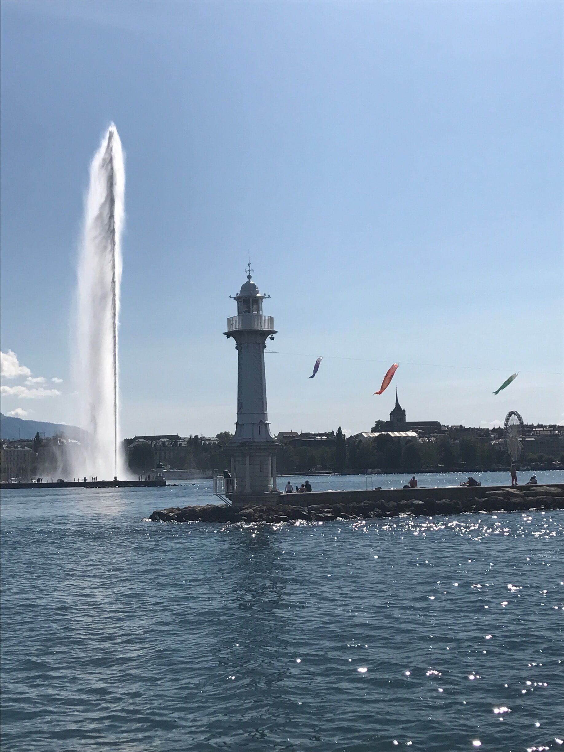 View from our boat trip on Lake Geneva, Geneva, Switzerland 🇨🇭 This is the lighthouse at the end of  Jetee des Paquis with the Jet d’Eau and the Ferris Wheel at Jardin Anglais in the background 🛥🎡