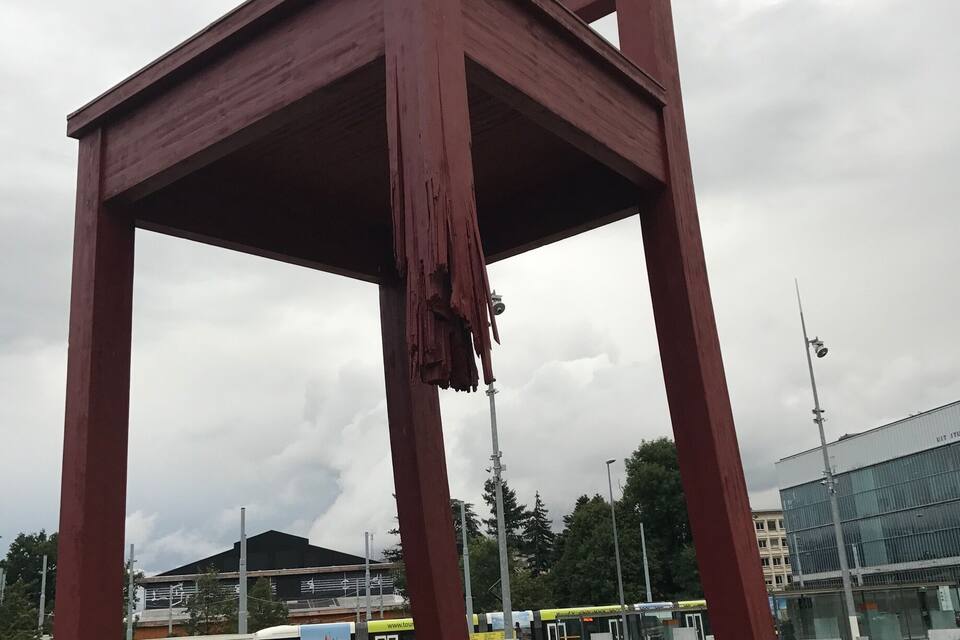 Une grande sculpture représentant un fauteuil rouge, installée sur une place publique.