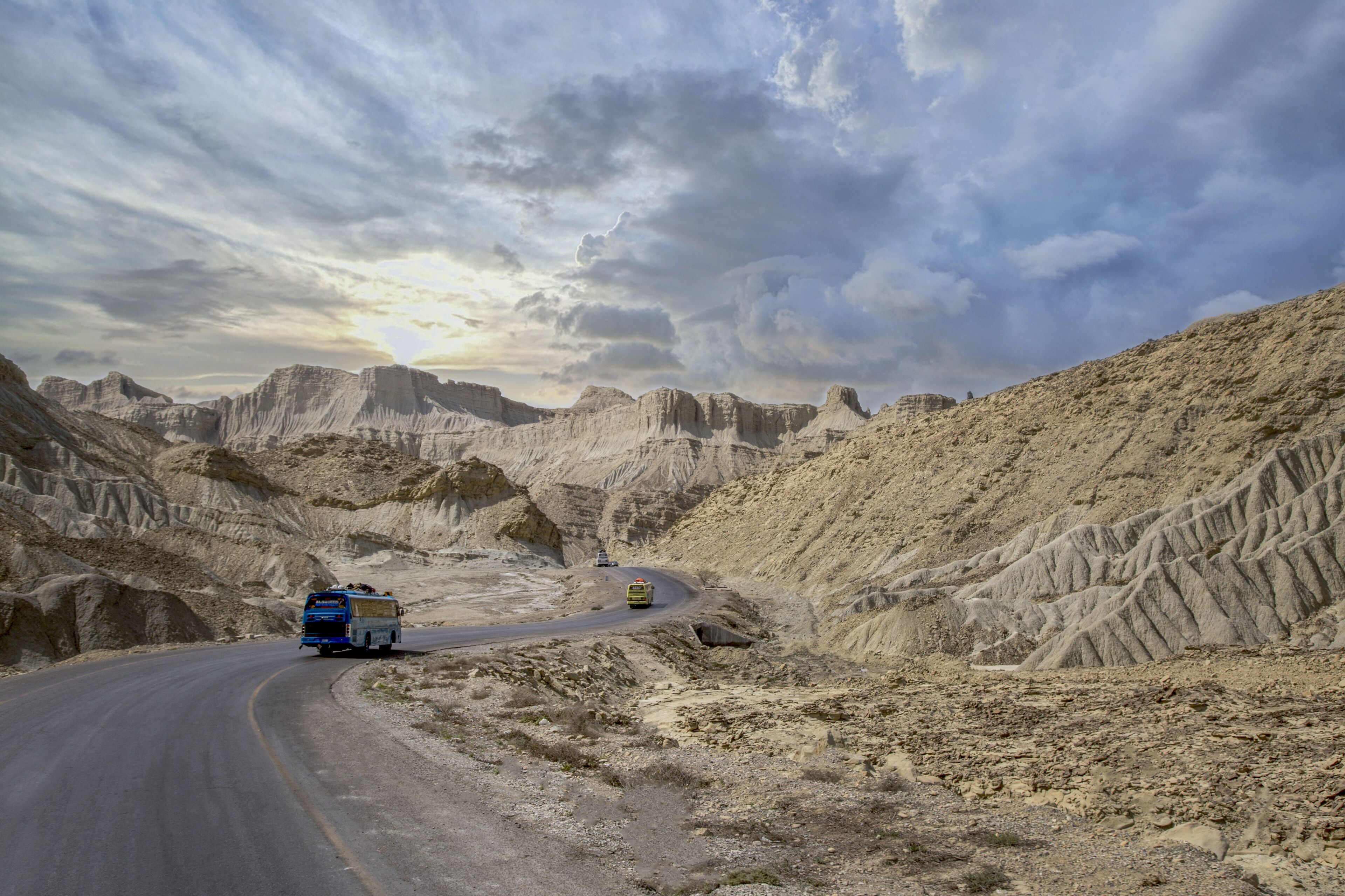 A winding road through a desert landscape with rocky terrain and sparse vegetation.