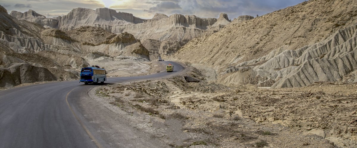A winding road through a desert landscape with rocky terrain and sparse vegetation.