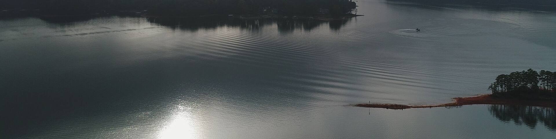 A calm lake with a distant shoreline and overcast sky.