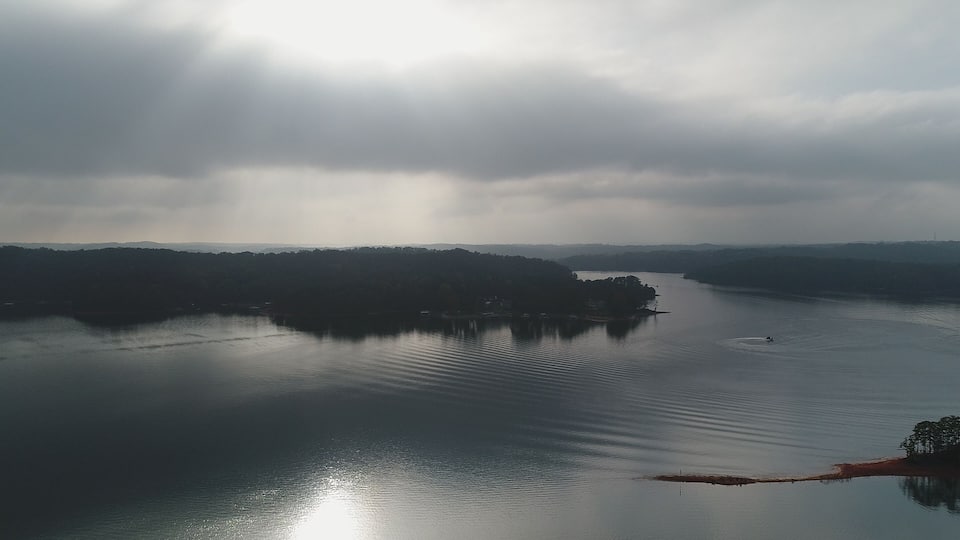 A calm lake with a distant shoreline and overcast sky.