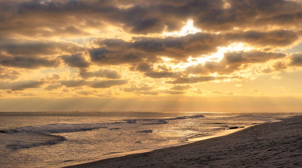 Beams of sun poking through clouds over a beach during sunset. Long Island New York panorama