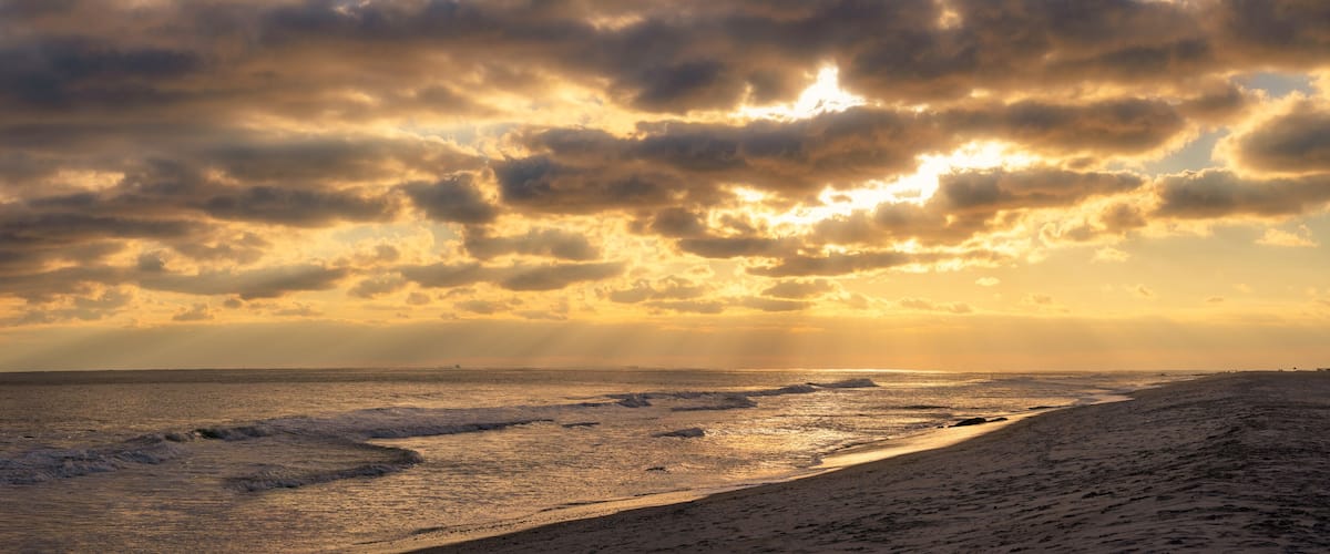 A beach with waves and a cloudy sky.