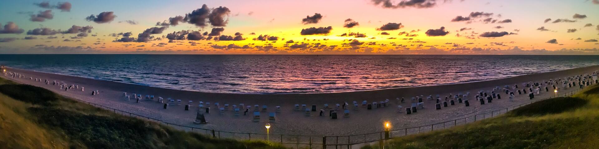 The beach of Westerland on the island of Sylt, Germany. Panoramic view at sundown with spectacular evening sky colors.