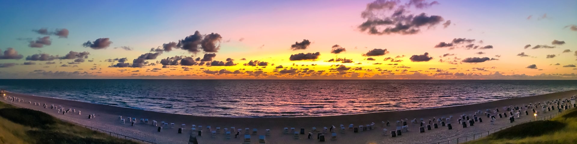 The beach of Westerland on the island of Sylt, Germany. Panoramic view at sundown with spectacular evening sky colors.