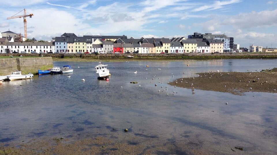 A waterfront with boats, a crane, and buildings along the shore.