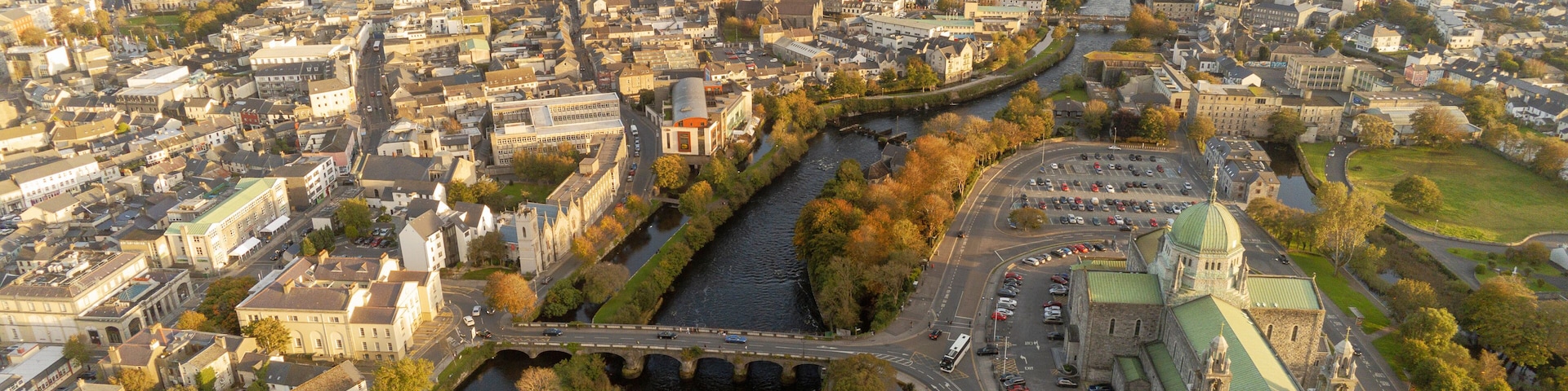 A river flowing through a city with historic buildings and a prominent church with a green roof.