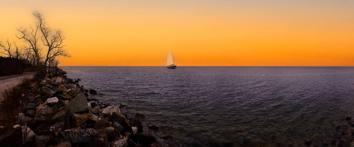 A sailboat on a calm sea during sunset.