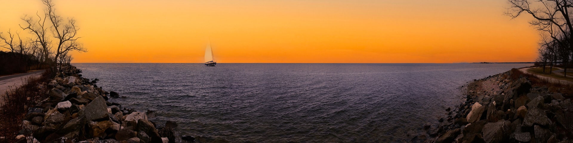 A sailboat on a calm sea during sunset.