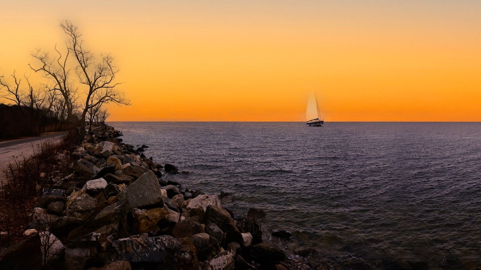 A sailboat on a calm sea during sunset.