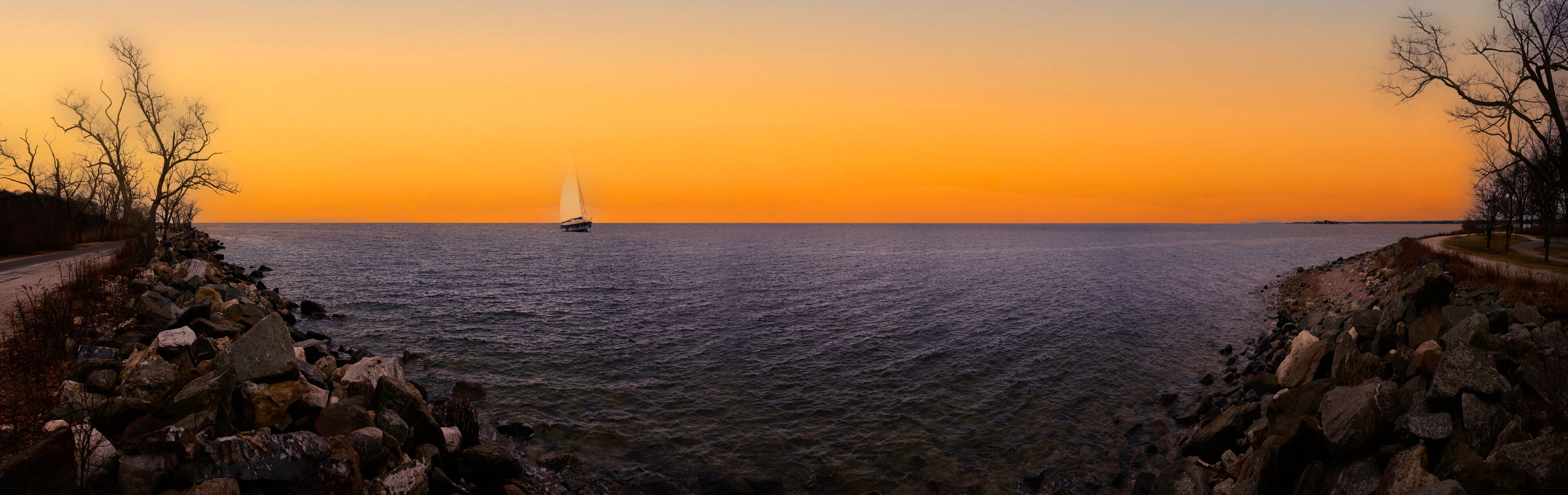 A sailboat on a calm sea during sunset.