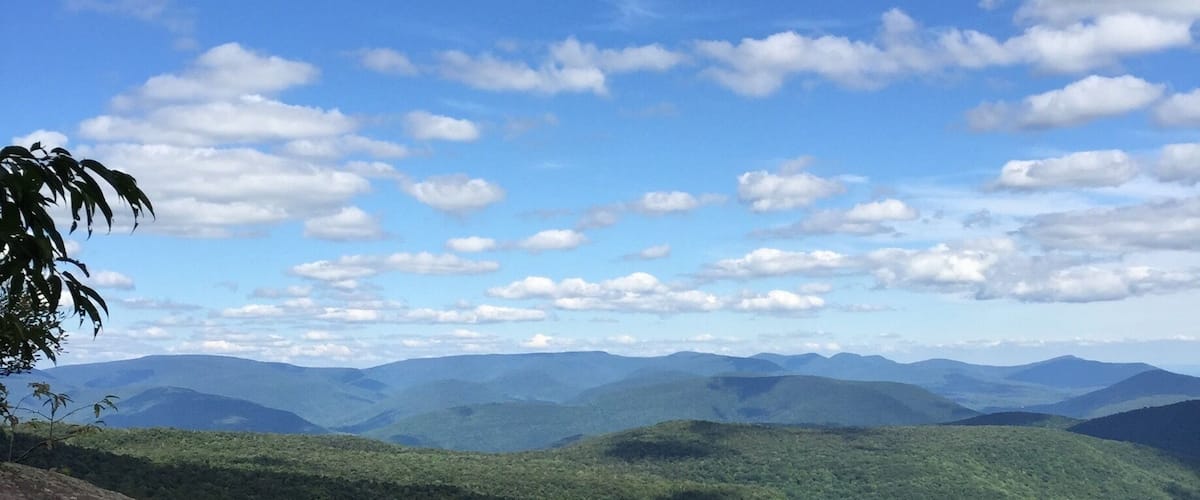 A mountainous landscape with a clear sky and scattered clouds.
