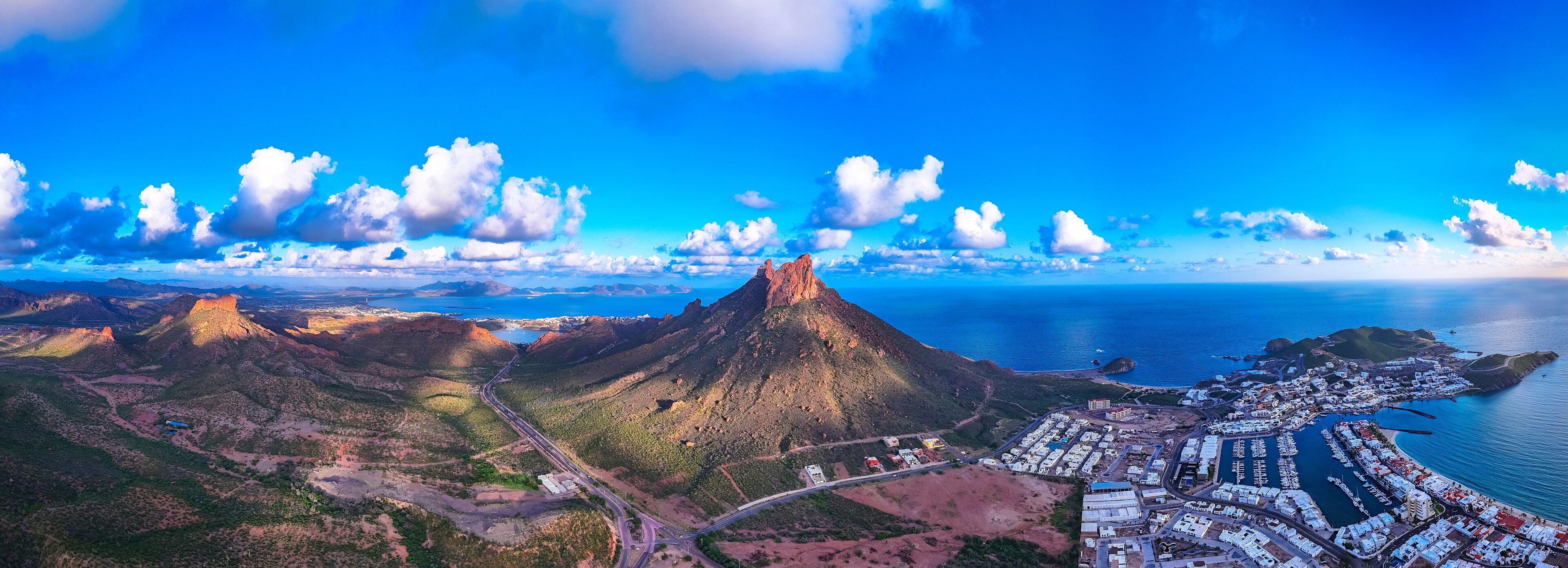Panoramic aerial view of San Carlos Sonora, Mexico, with its iconic Tetakawi Mountain in the center, the yacht club to the right and the desert to its left.
