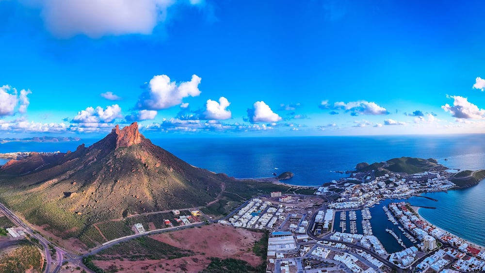 A coastal town with a prominent mountain, a marina, and a winding road.