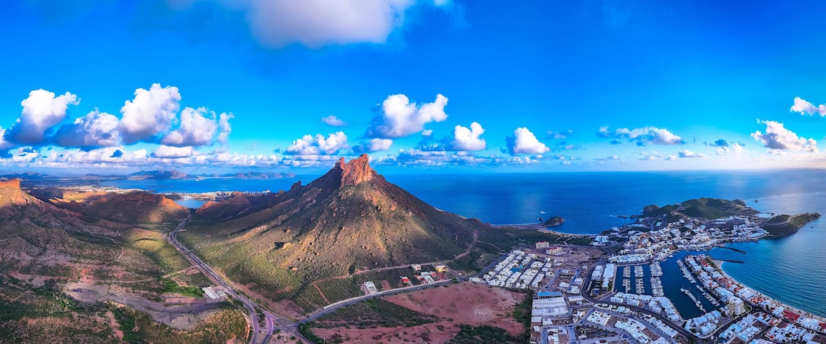 A coastal town with a prominent mountain, a marina, and a winding road.