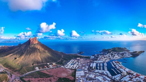 A coastal town with a prominent mountain, a marina, and a winding road.