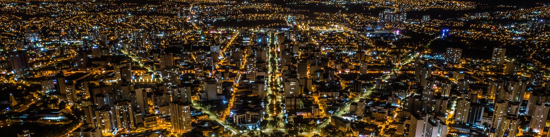 A nighttime aerial view of a densely populated city with illuminated streets and buildings.