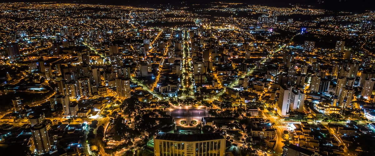 A nighttime aerial view of a densely populated city with illuminated streets and buildings.
