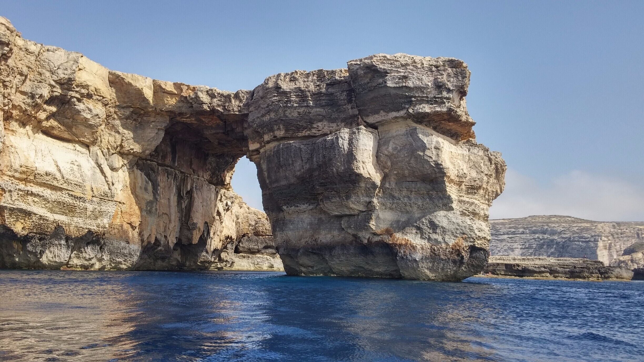 A large rock formation with a natural arch over the sea.