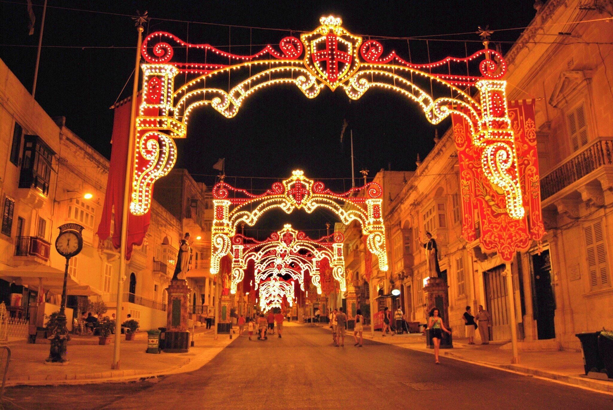 A street with ornate light decorations and a clock.