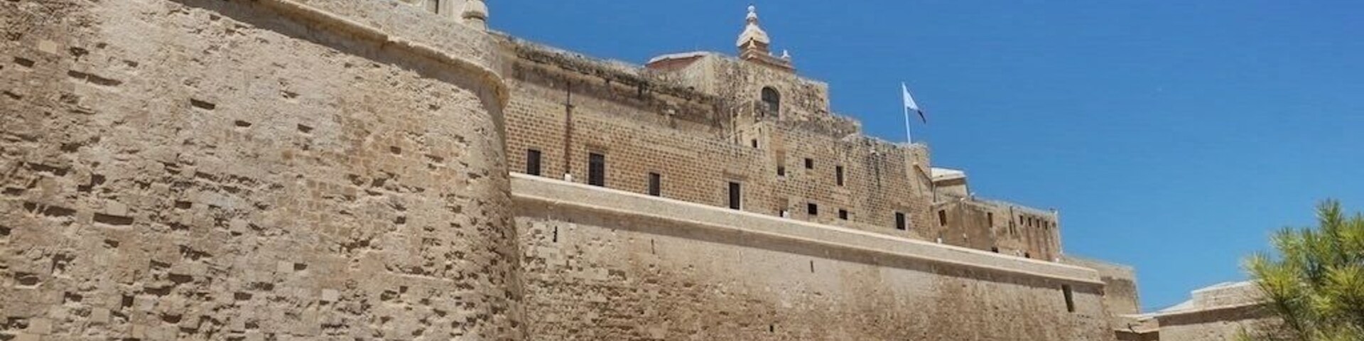 Una fortaleza de piedra histórica con almenas y un asta de bandera.