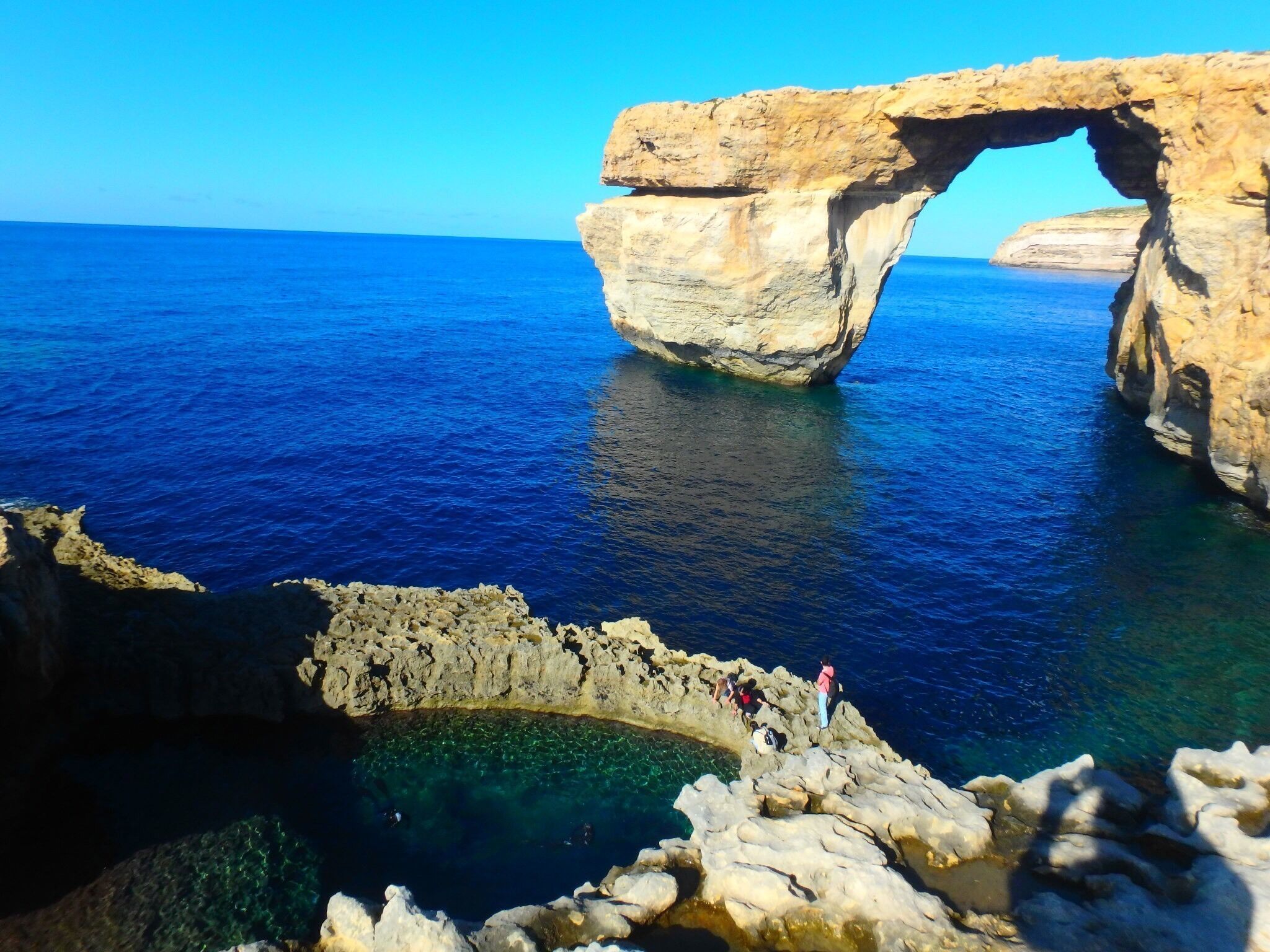 A large rock formation with a natural arch over the sea.