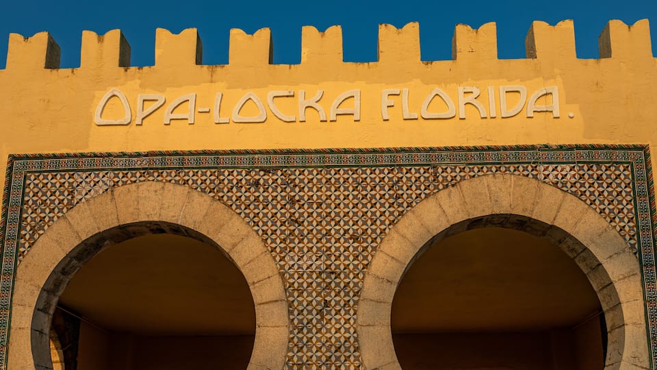 A building facade with the inscription "OPA-LOCKA FLORIDA" and two large arches with intricate tile patterns.