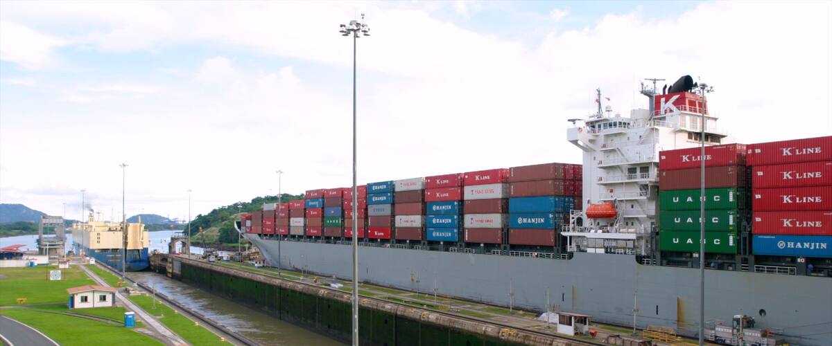 A large cargo ship docked at a port with multiple shipping containers stacked on its deck.