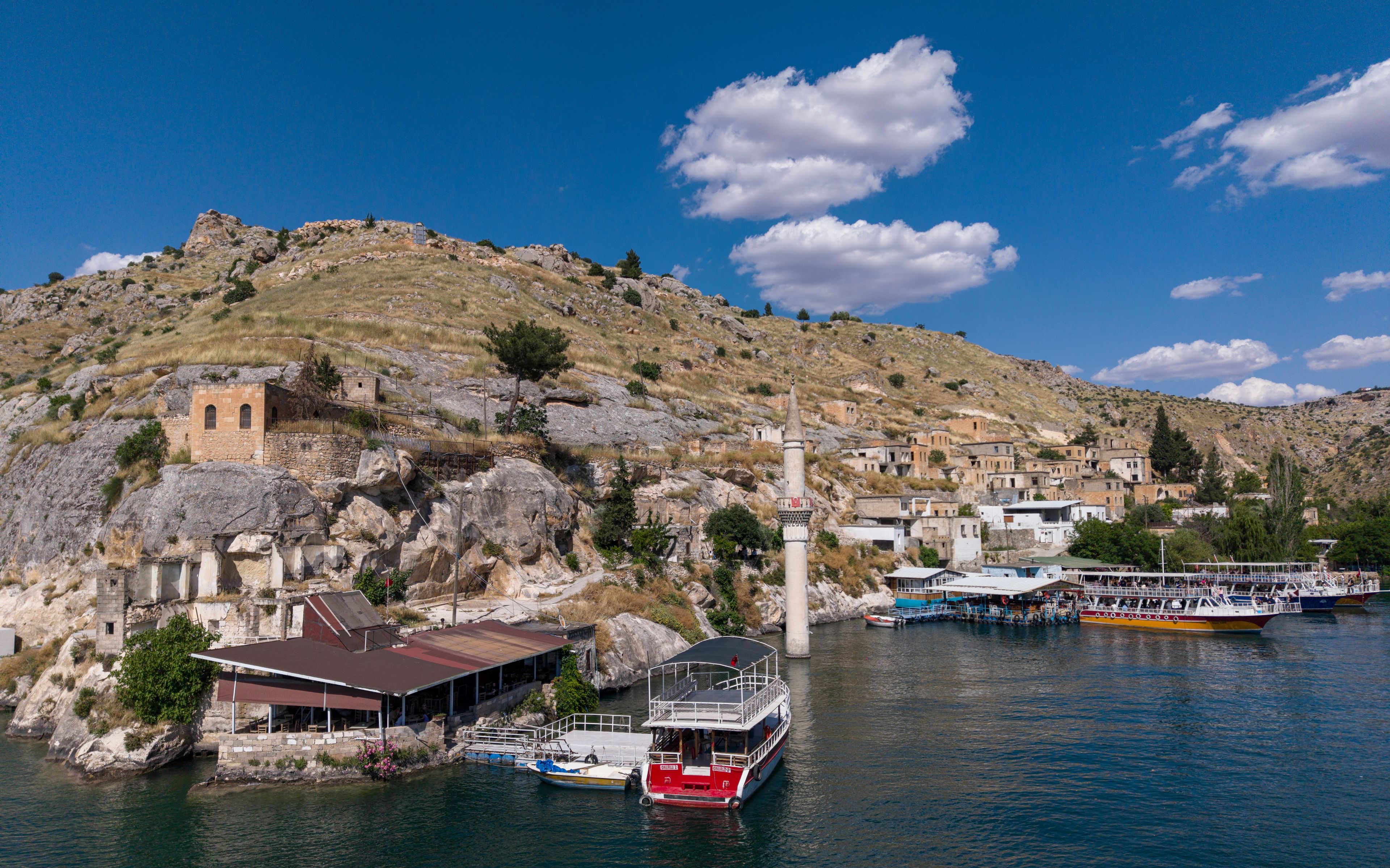Un pueblo costero con edificios históricos, una torre destacada y barcos amarrados en el puerto.