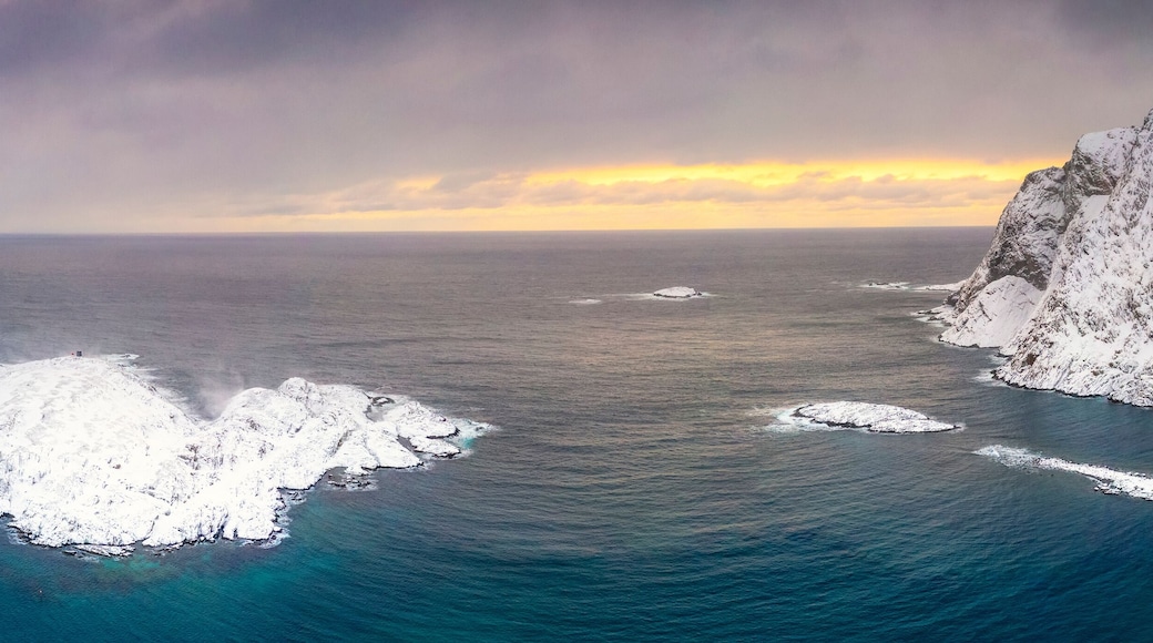 Waves of cold sea framed by snow capped mountains at dawn, aerial view, Sorvaer, Soroya Island, Hasvik, Troms og Finnmark, Arctic