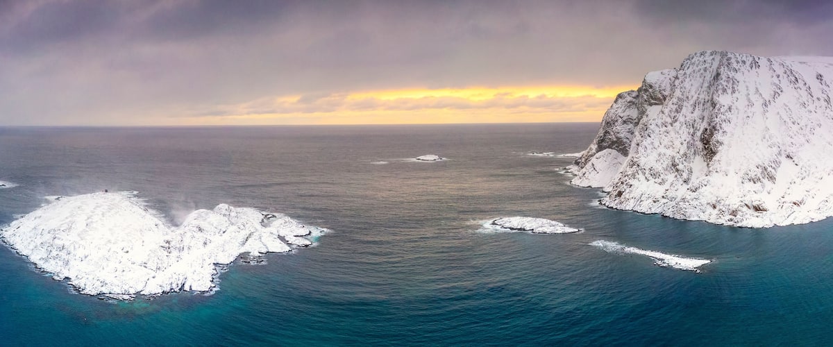 A snow-covered cliff and ice formations in the ocean.