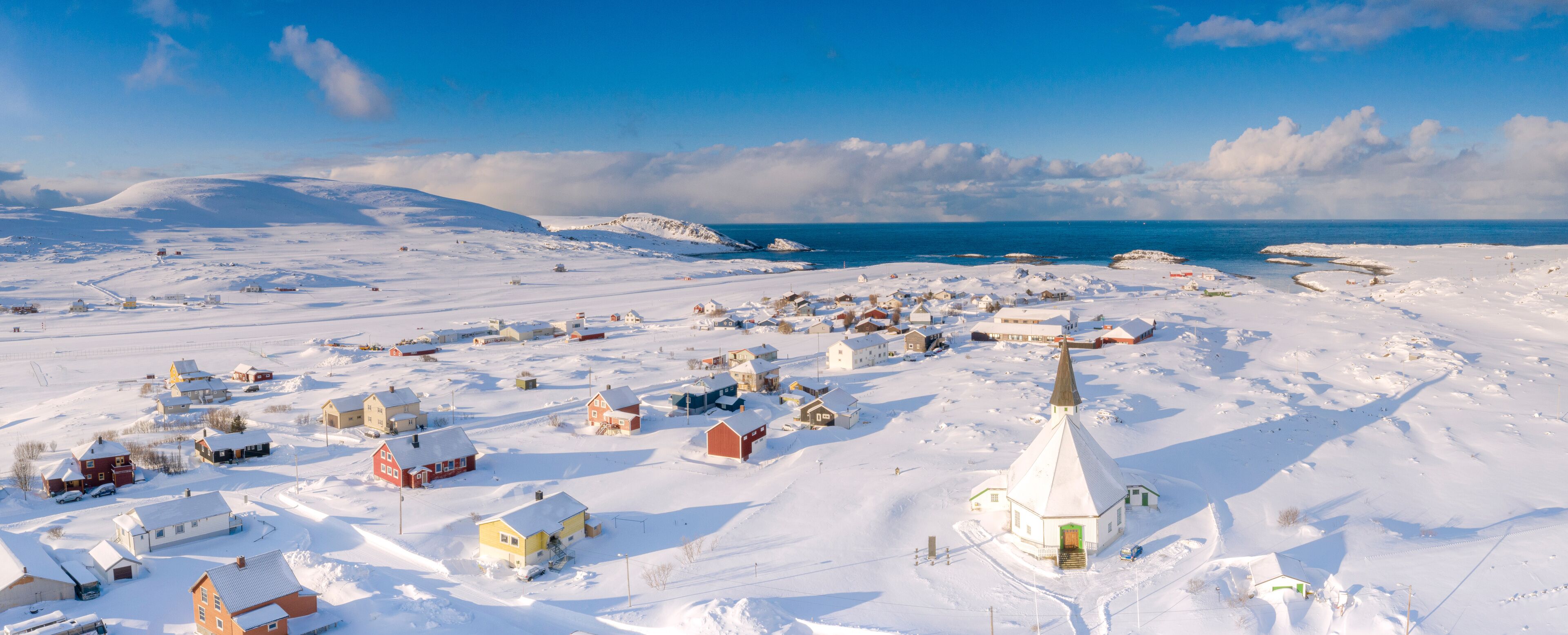Aerial view of traditional houses and church in the small village of Hasvik after a snowfall, Troms og Finnmark