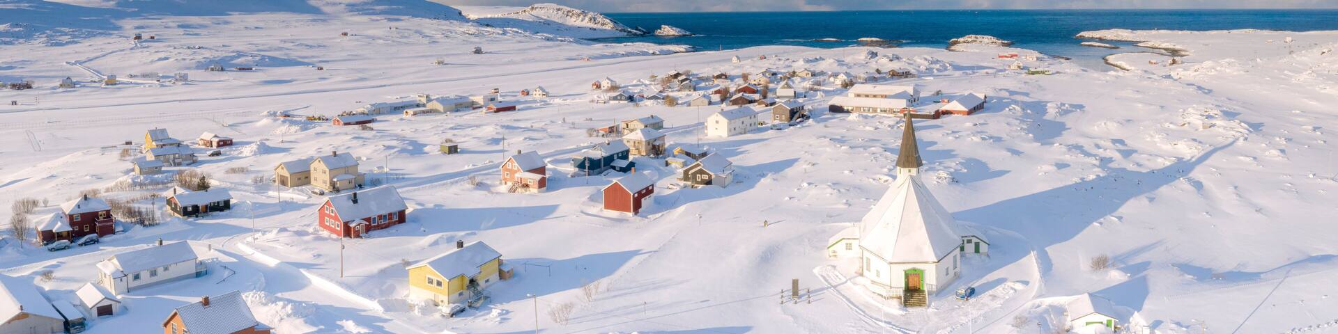 Aerial view of traditional houses and church in the small village of Hasvik after a snowfall, Troms og Finnmark