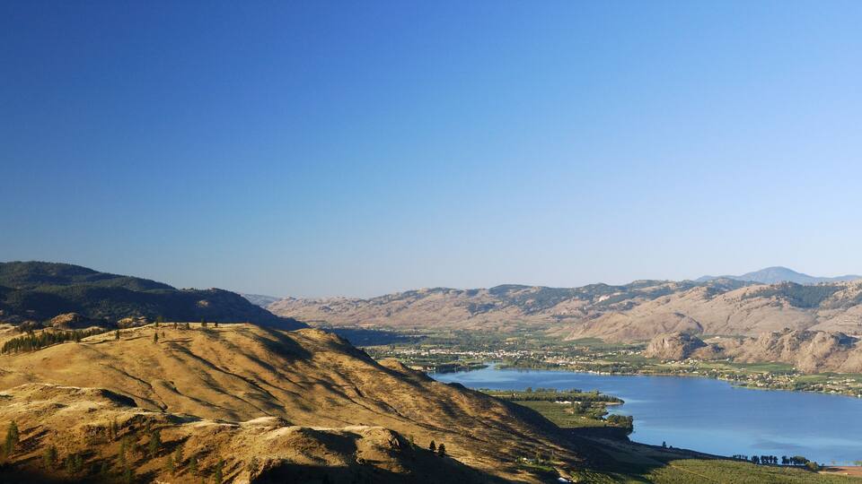 A mountainous landscape with a lake and a town in the valley.
