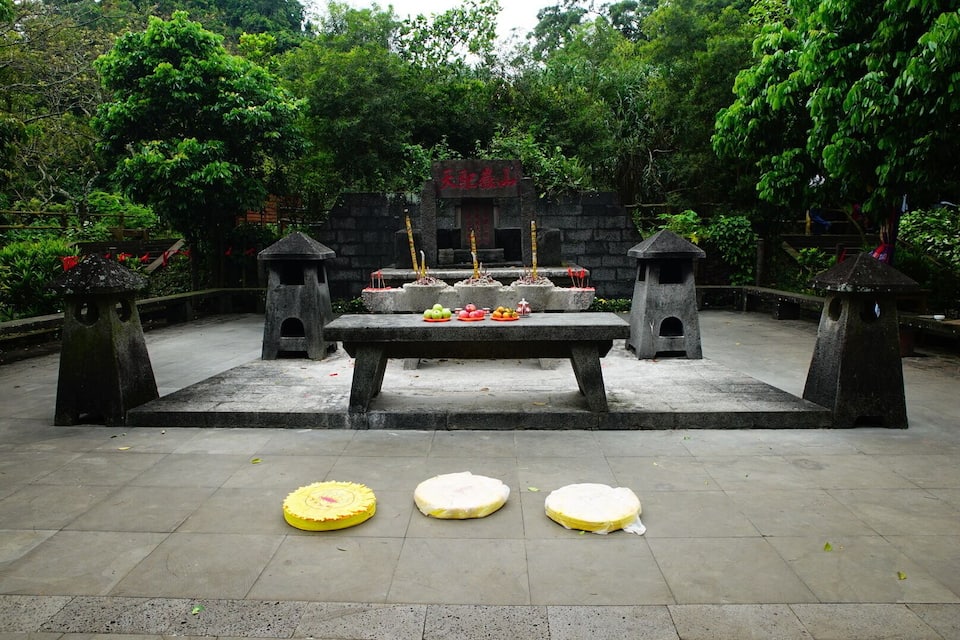 A stone altar with offerings in a temple surrounded by trees.