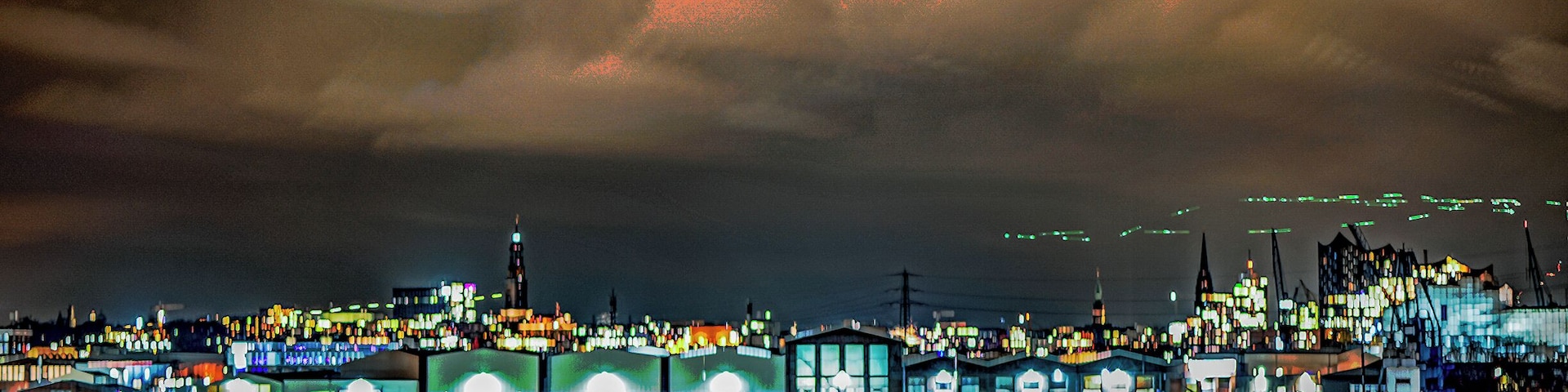 Uma paisagem urbana noturna com edifícios iluminados e um céu nublado.