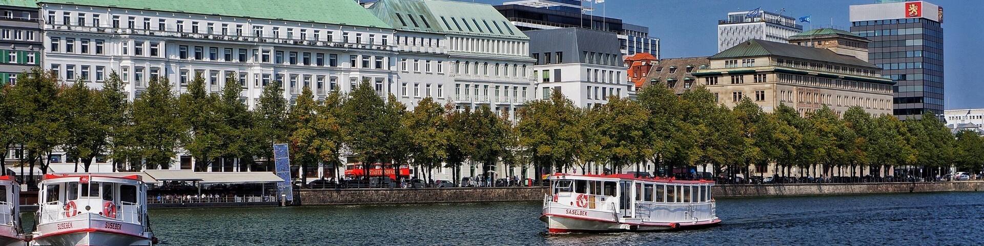 A river with boats, a large building with flags, and a modern skyscraper.
