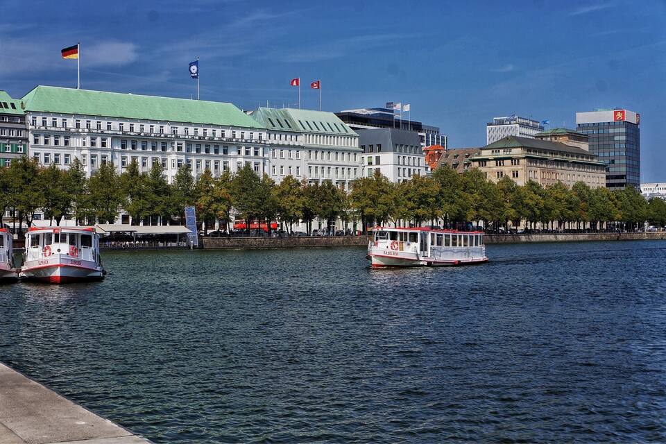 Ein Fluss mit Booten, ein großes Gebäude mit Flaggen und ein moderner Wolkenkratzer.